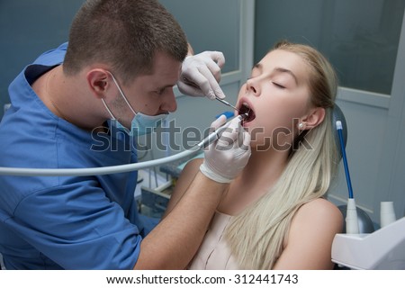 Photo of pretty girl with the dentist over her holding drilling instrument and mirror