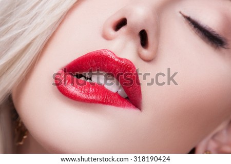 Sexy Lips. Beauty Red Lips Makeup Detail. Beautiful Make-up Closeup. Sensual Open Mouth. Beautiful blonde girl bit her lip passionately, white teeth