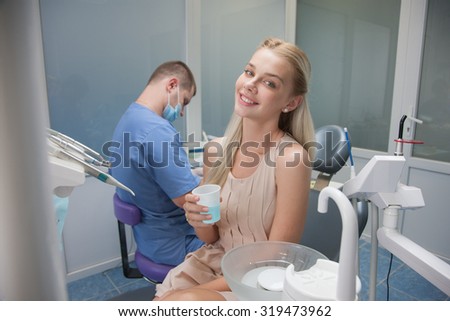 The girl at the dentist. Dentist holds the tools, limited to users sitting in an armchair at the doctor. The girl at the dentist at the reception sitting in a chair, rinse the teeth with liquid
