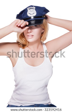 Attractive female police officer\'s cap on her head. Beautiful girl in a police cap on a white background with light make-up on her face. Girl holds hands behind his cap. police woman