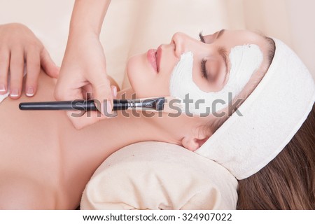 Female face closeup girl mask is applied with a brush. Beautiful girl in a beauty salon on the procedures for rejuvenation, skin lifting. Lovely woman with soft skin lying on his back in the salon spa