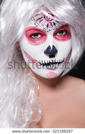 Halloween makeup so women in the image on her head a white wig. Stylish Grimm on the face of the girl for a holiday All Saints\' Day.Painted mask for carnival.Portrait drawing of a skull on his face