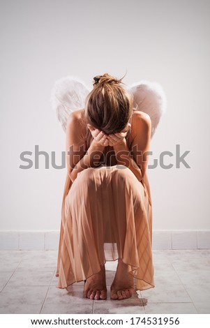 Lonely angel sitting on the chair and crying.