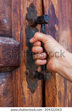 Wooden door with a hand on handle.