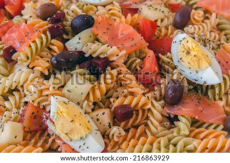 Top view of a pasta salad with olives, tomato, beetroot, cucumber, smoked salmon and boiled egg