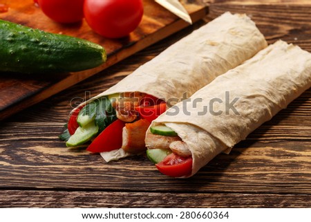 Traditional shawarma wrap with chicken and vegetables near its ingredients