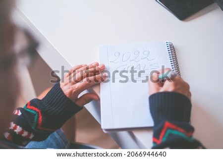 Planning, motivation for the new year 2022. Hands of old woman writing new year 2022 goals in diary. Word writing text 2022 Goals in a notebook. Business or personal goals for new year