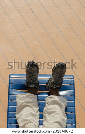 View of the feet of a man lying on a deck chair