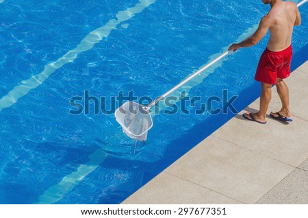 A man cleans the swimming pool. Summer maintenance service