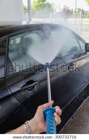 A woman is washing a car with flowing water. Hand made job