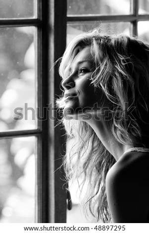 Beautiful young woman sitting by cottage pane window