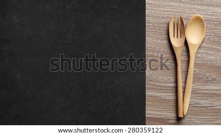 Wooden Spoon and Fork on wood Table with side is Black place mat. Menu Set Concept