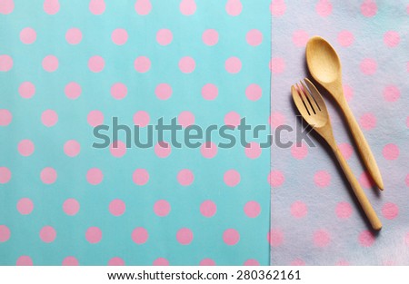 Wooden spoon and fork on pink paper and paper placemat  pattern pink dot and cyan background. Menu set Concept