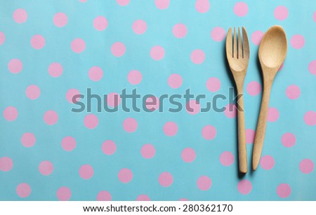 Wooden spoon and fork on paper placemat  pattern pink dot and cyan background. Menu set Concept