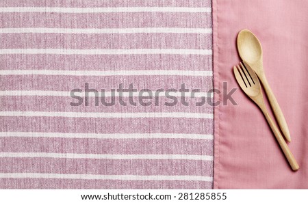 Wooden spoon and fork on pink towel and pattern pink towel background