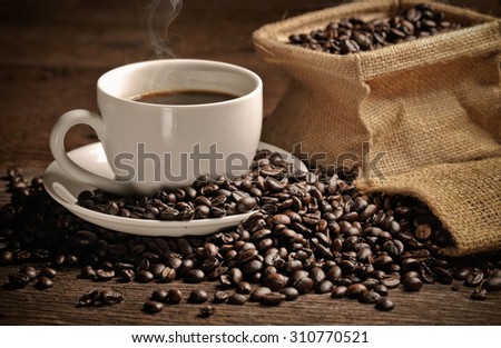 warm cup of coffee with sack inside by coffee bean on wood background