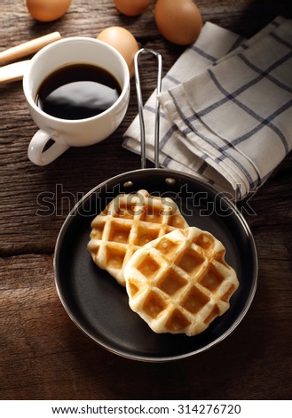 Fresh Waffles and hot coffee for breakfast set with eggs and wood background