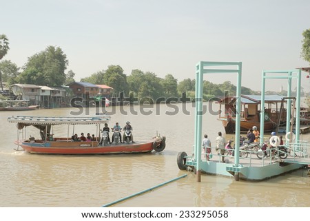 Ayutthaya, Thailand - November 23rd: Small ferry unloading motorcycle onto small pier on 23/11/2014 in Ayutthaya province. The sign above ferry state maximum capacity is 12 people.