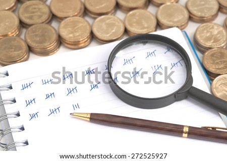 Abstract pile of money around ring bound book with mark showing amount of counted money