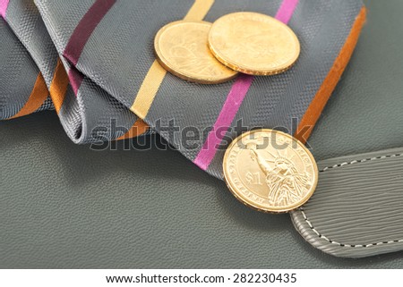 Abstract contrasty closeup of three dollar coins over necktie on top of leather business book