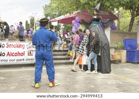 Bangkok, Thailand - July 5, 2015 : Student dress as witch and clown to promote their renew news paper. The audience ask clown to help take a photo with her iPhone