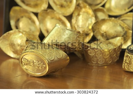 Abstract closeup of tilted treasure box with chinese style gold bar leaking out. The chinese words are crafted into gold with meaning of good fortune, best of luck, and good health.