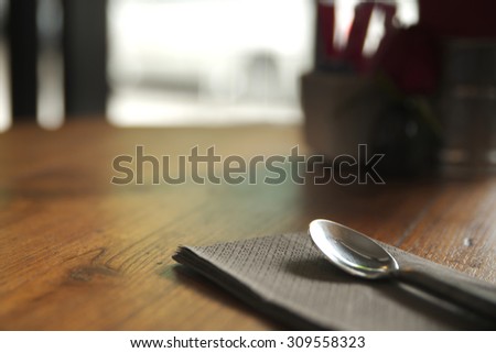 Abstract close up of silver spoon over brown paper napkin on top of table