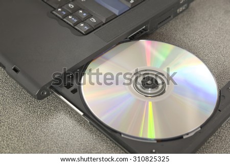 New shiny CD/DVD inside optical disk drive bay of black laptop