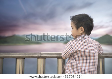 Abstract concept of boy in sulky mood looking away into wild dramatic ambient park