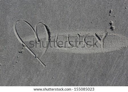 name Lucy written on beach, authentic photo of grey sandy beach of island Ameland, Netherlands, Europe