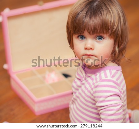 little girl sitting next to the open box.
