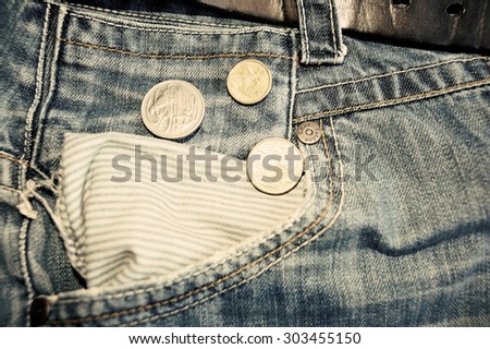 Old jeans and australian dollars coins near empty pocket