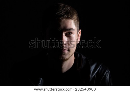 Photo of the young man in shadow on black background