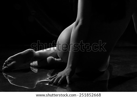 Black and white photo of woman's body on the floor on black background
