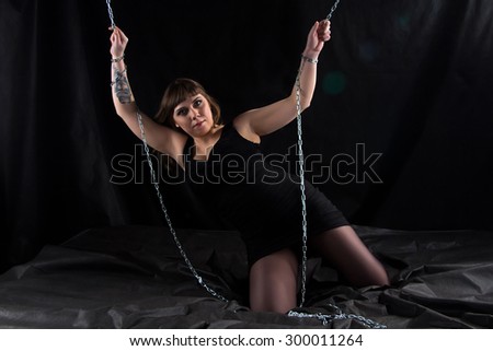 Photo of leaned one side woman holding chains on black background