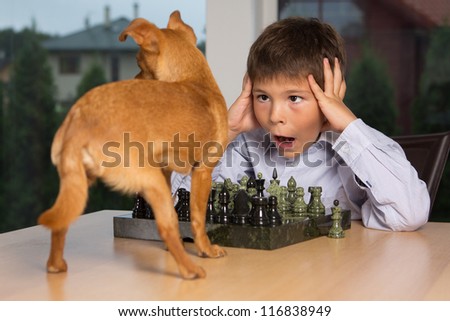 Image of little kid playing chess with dog