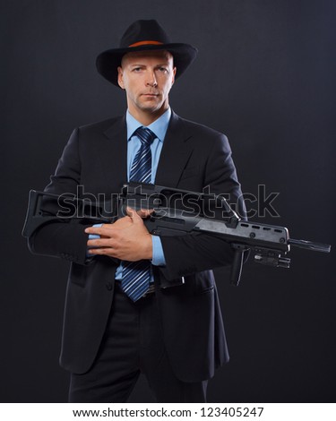 Portrait of sexy man posing in studio in suit with gun