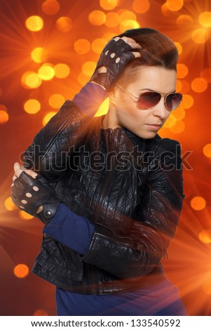 Image of rock diva in leather clothing shined with orange lights