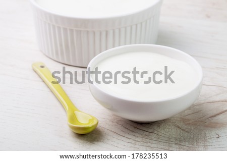 A yellow spoon and two white bowls with milk