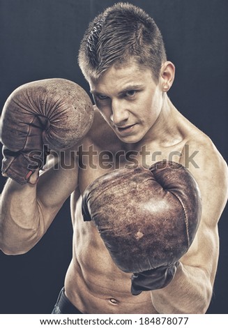 Handsome guy with old boxing gloves over a black background