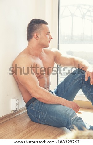 Man in jeans sits by the window