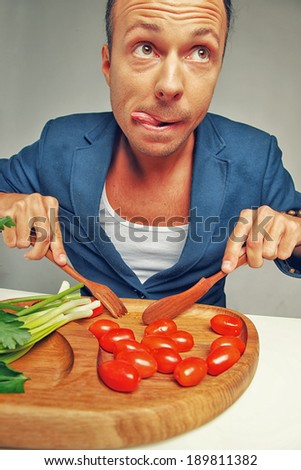 A hungry man in a blazer cutting tomatoes
