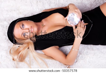 image of sexy model lying on fur fell with diamond in hands