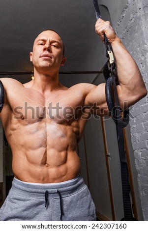 Strong muscular man bodybuilder poses and shows his abs