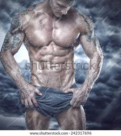 Muscular man showing his body in stormy weather