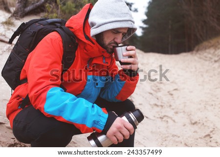 Hiker drinks tee holding vacuum bottle