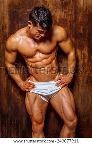 Muscular and good shaped young bodybuilder poses over the wall