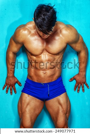 Muscular and good shaped young bodybuilder poses over the wall