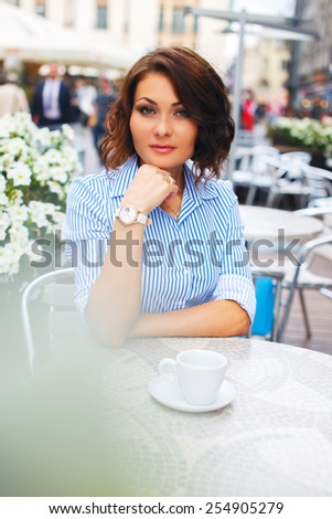 Woman in blue blouse sitting in street cafe.