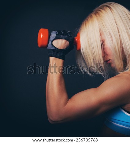Good-shaped athletic girl stands and holds dumbbell